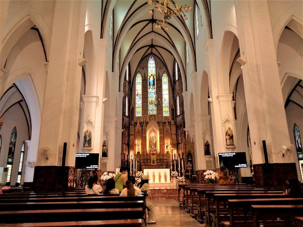 Inside the cathedral, warm light filters through stained glass, filling the space with quiet beauty